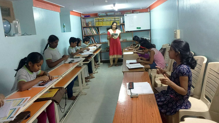Picture of a lady teacher teaching abacus to young students at AbacusMaster, Bangalore branch