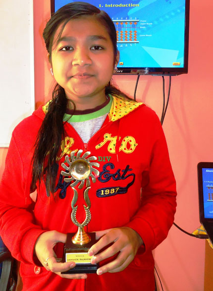 Picture of a student posing with the trophy she won at an abacus competition at AbacusMaster, Guwahati branch