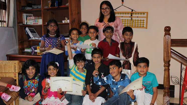 Picture of a lady teacher posing with young students with their certificates at AbacusMaster, Kodaikanal branch