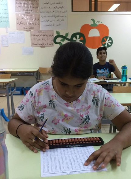 Picture of a student working out problems on an abacus board during abacus certification exam at AbacusMaster, Muscat branch