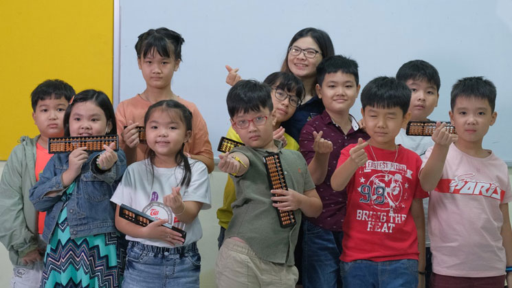Picture of students posing with an abacus board for a picture at AbacusMaster, Vietnam branch