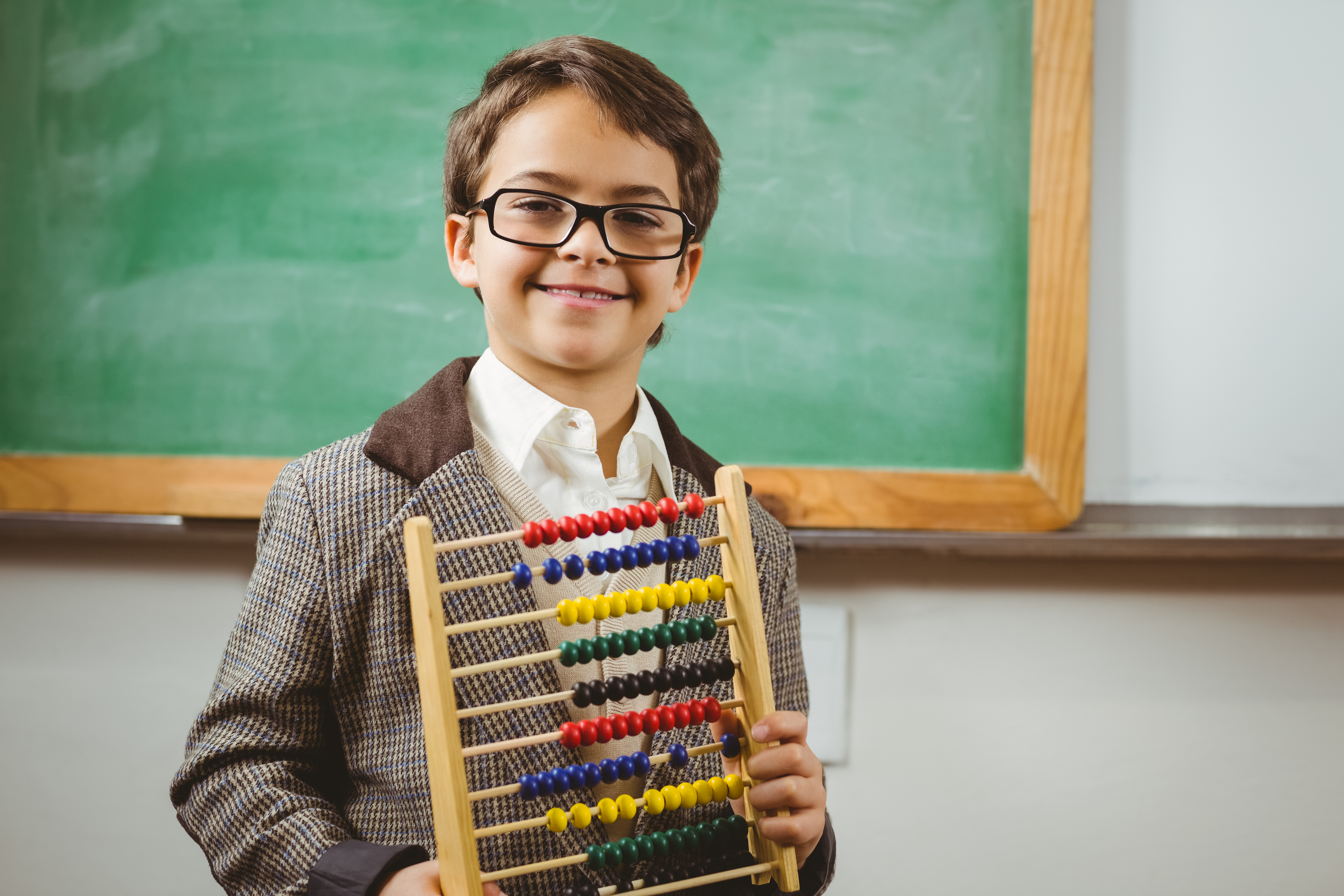 Boy holding abacus in classroom