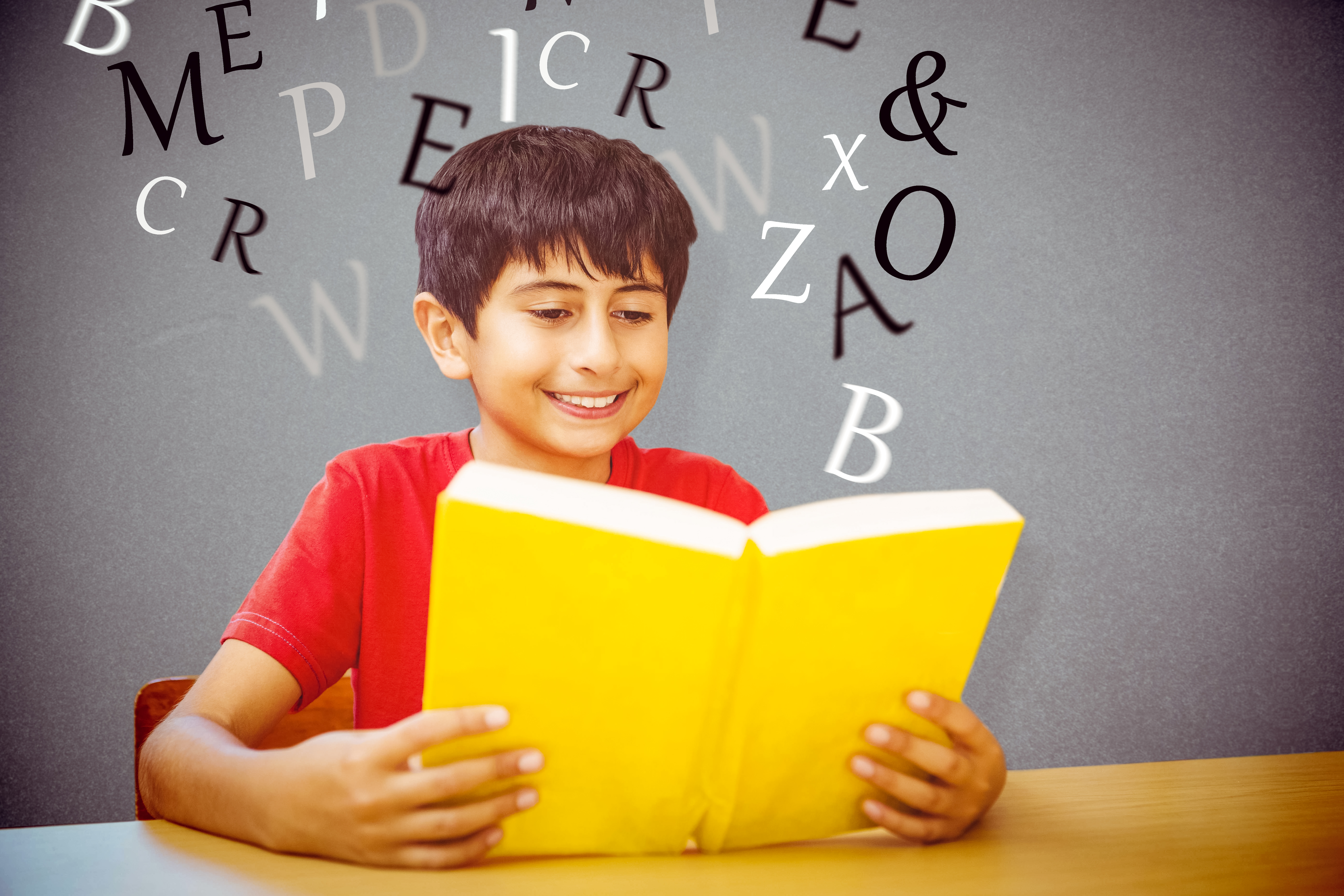 Boy reading book against wall