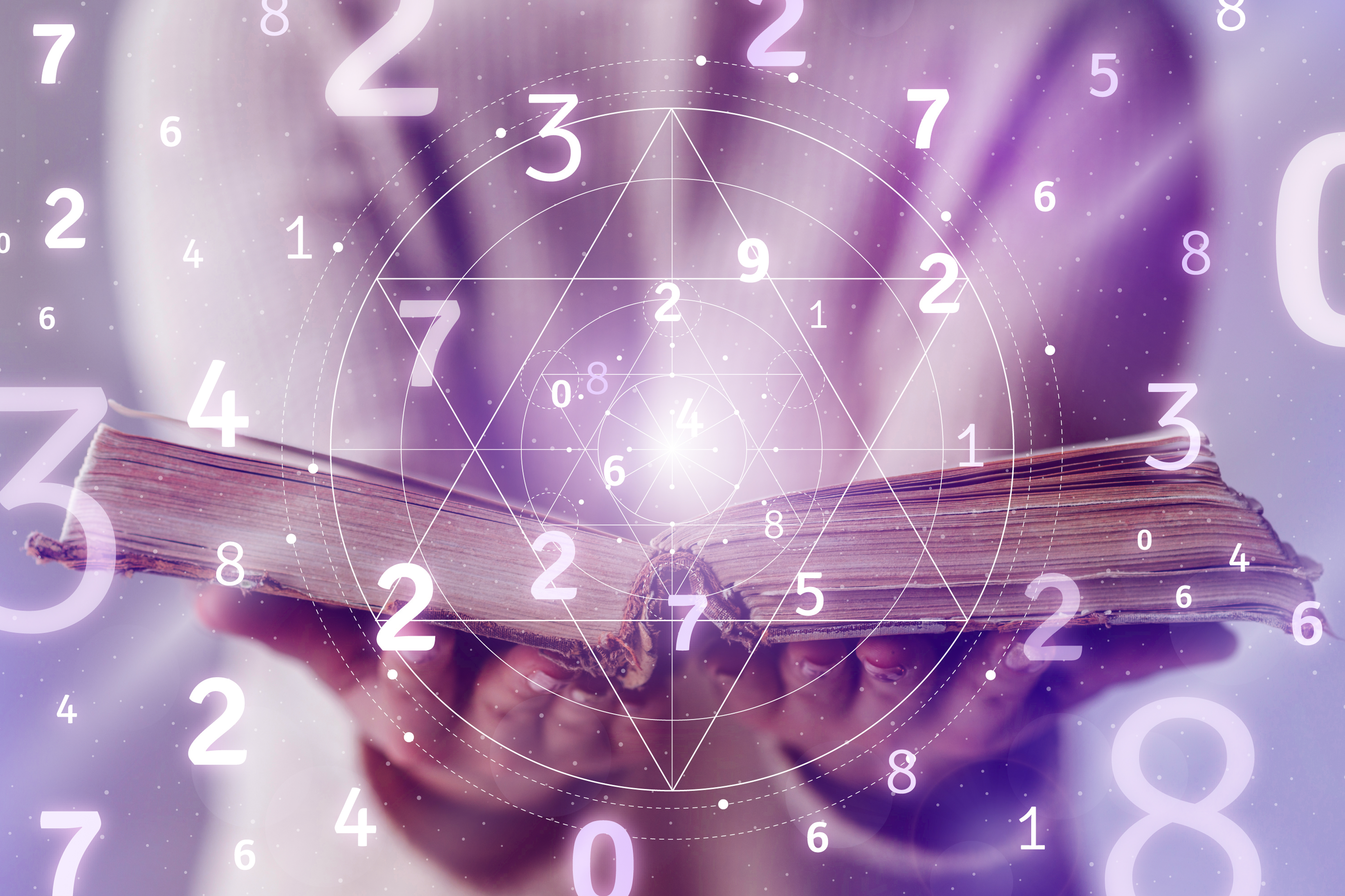 A person studies a book of numbers and geometric patterns.