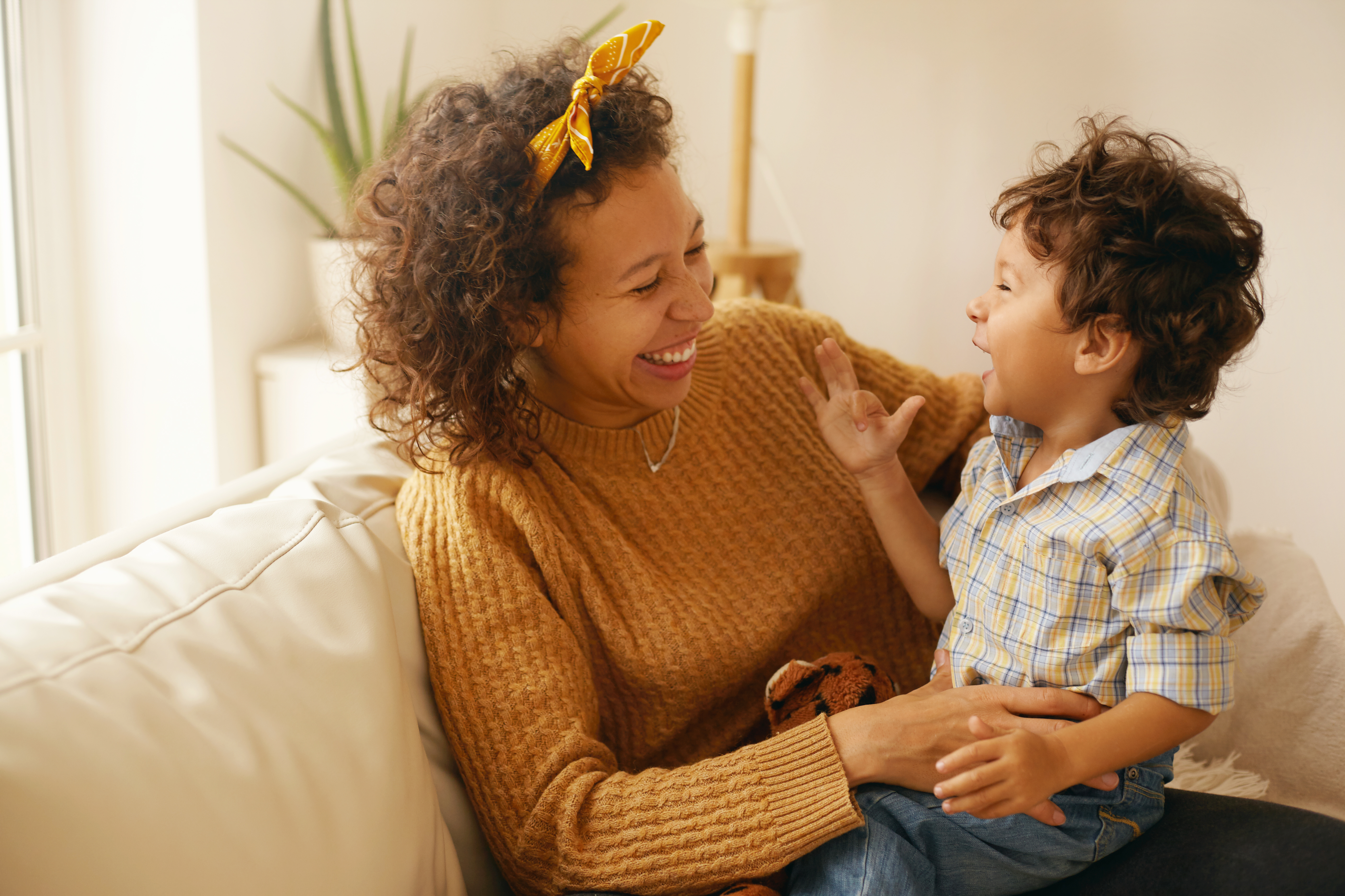 A mother and young child smiling and talking together on a sofa, capturing a warm learning moment at home — perfect for illustrating early word learning and the importance of a strong vocabulary foundation in an English vocabulary class or online learning environment.